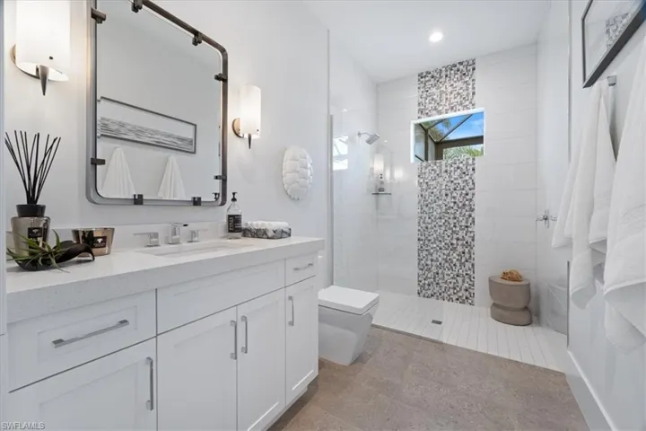 Bathroom with a tile shower, vanity, and toilet