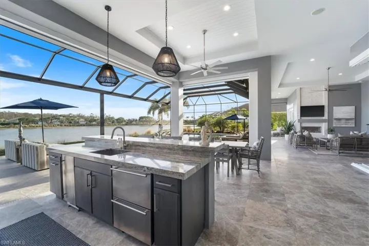 View of patio / terrace featuring ceiling fan, a lanai, an outdoor wet bar, and a water view