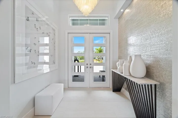 Foyer with a chandelier, french doors, and light tile patterned floors