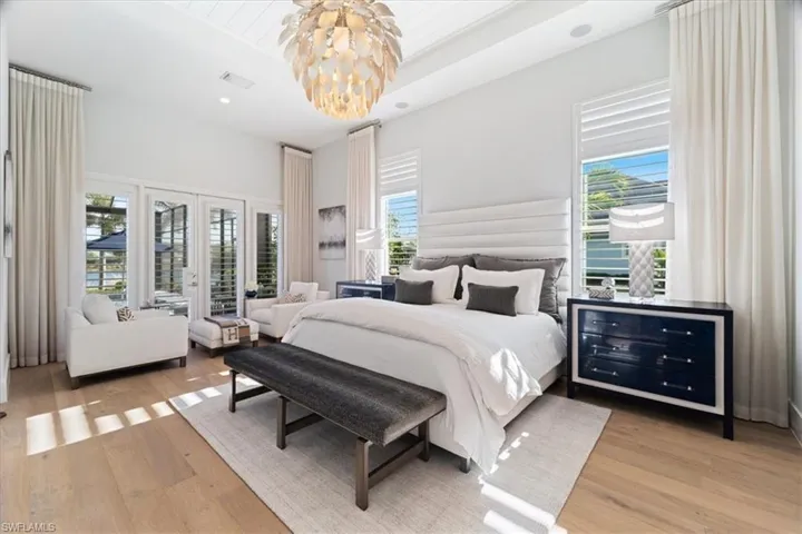 Bedroom featuring french doors, light hardwood / wood-style floors, and an inviting chandelier