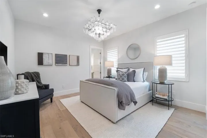 Bedroom featuring a notable chandelier, connected bathroom, and light hardwood / wood-style flooring