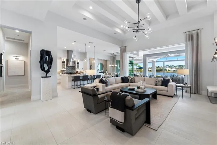 Living room with beam ceiling, light tile patterned floors, and a notable chandelier