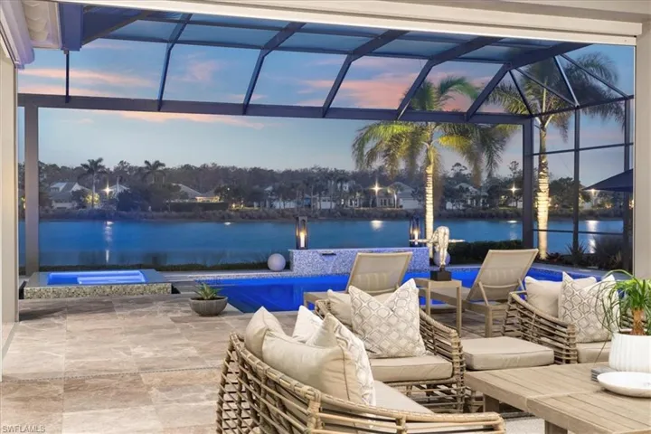 Patio terrace at dusk featuring glass enclosure, a water view, and an outdoor hangout area