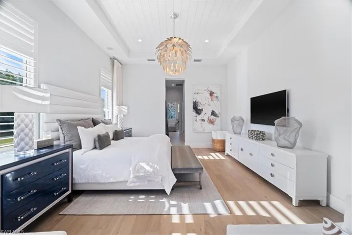 Bedroom with a tray ceiling, light hardwood / wood-style flooring, multiple windows, and wooden ceiling