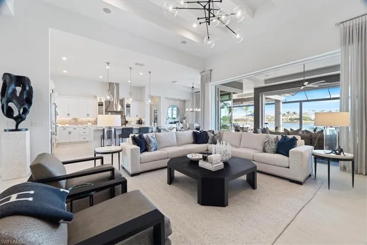 Tiled living room with a water view and ceiling fan with notable chandelier