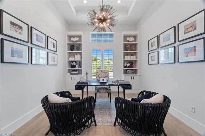 Office featuring a chandelier, built in shelves, a tray ceiling, and light hardwood / wood-style floors