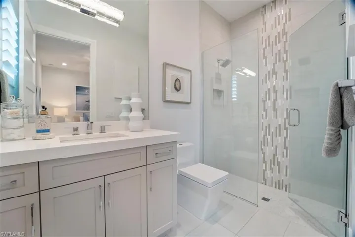 Bathroom featuring tile patterned floors, vanity, toilet, and a shower with door