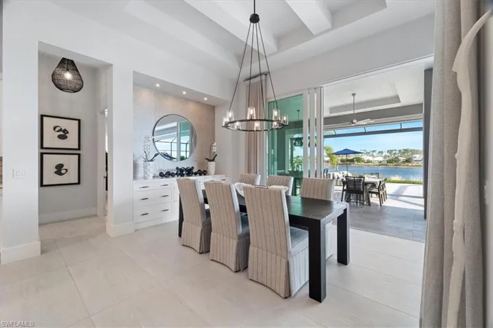 Dining area with light tile patterned floors, a water view, a raised ceiling, and a wealth of natural light