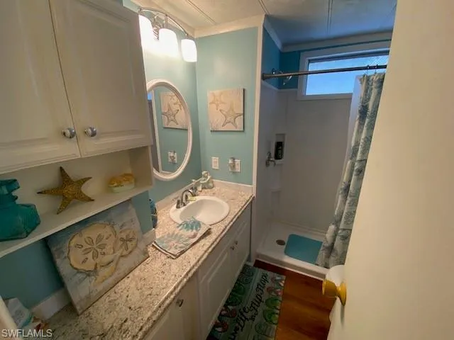Full bathroom featuring a shower stall, vanity, and crown molding