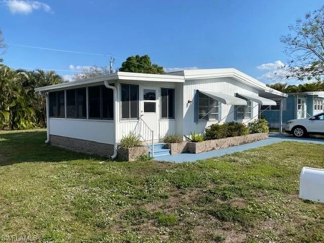 View of side of home featuring a sunroom and a lawn