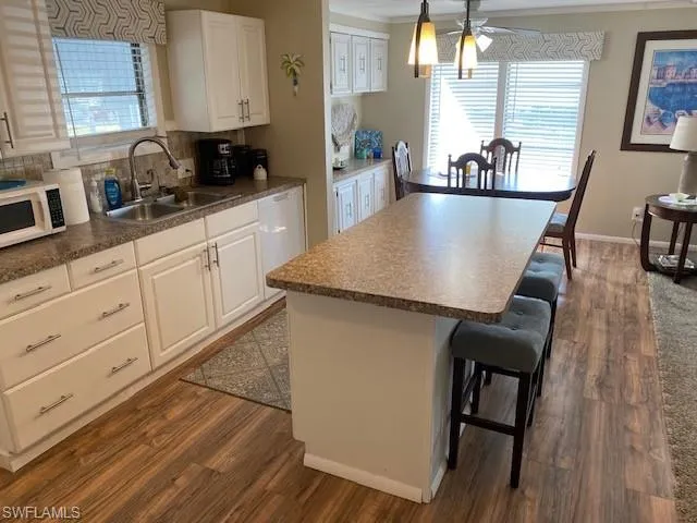 Kitchen featuring dark countertops, white cabinetry, a kitchen island, dark wood-style flooring, and ornamental molding