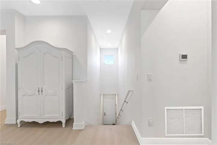 Hallway featuring an upstairs landing, light wood-style flooring, and recessed lighting