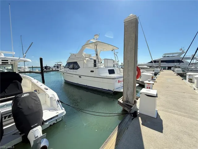 Dockside setting featuring a white hull vessel with multiple windows, a flybridge, and a transom