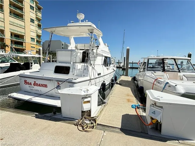 Dockside boat slip featuring a white vessel with transom, adjacent to a concrete pier