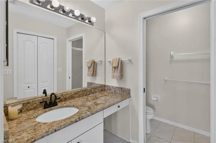 Bathroom vanity featuring an oval undermount sink, a granite-finish countertop, and a dark bronze faucet