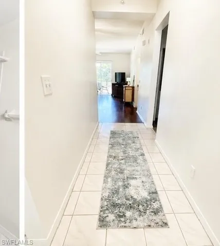 Hallway featuring square-format tile flooring and light-toned wall finishes