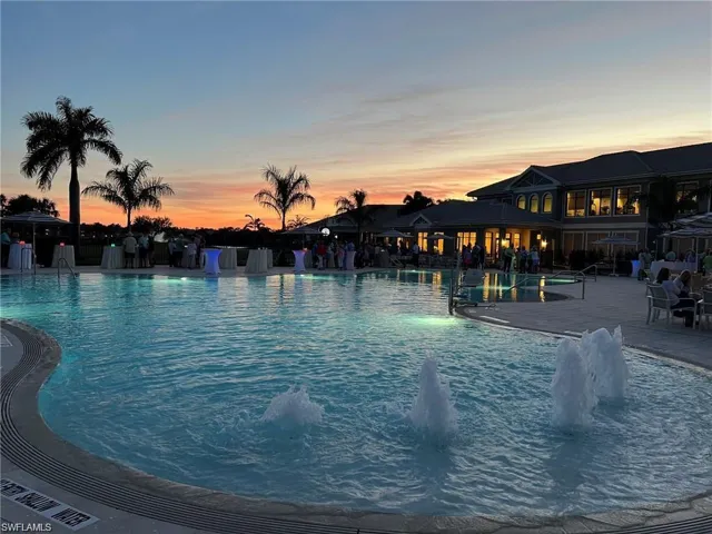 Resort-style swimming pool featuring multiple water fountains, integrated lighting, and a surrounding paved deck