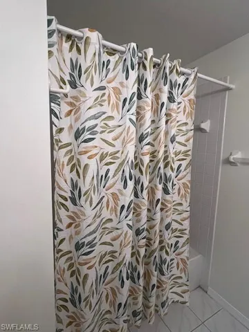 Tub-shower combination featuring white subway tile surround and coordinating white floor tiling