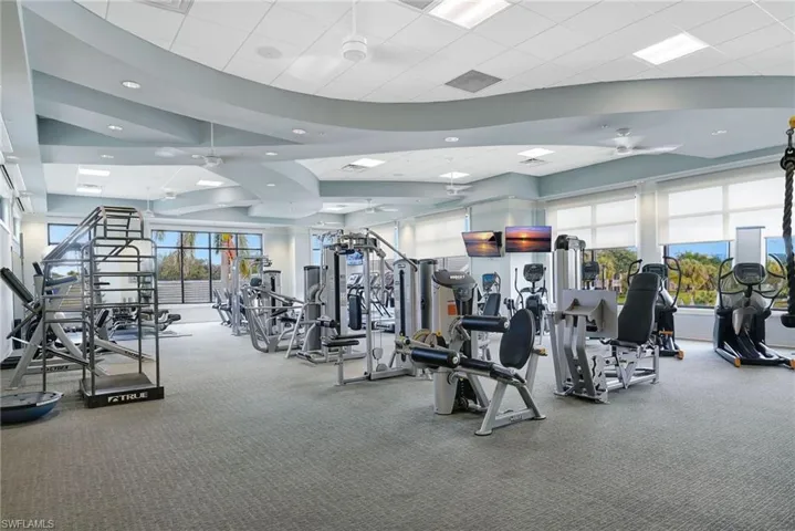 Spacious fitness center featuring a variety of exercise equipment, carpeted flooring, and expansive windows