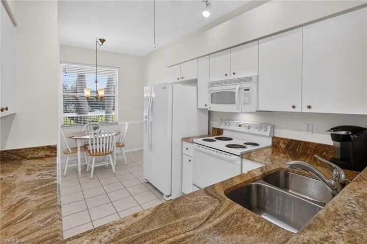 Kitchen featuring extensive counter space, white cabinetry, a built-in microwave, an electric range, and a double basin sink