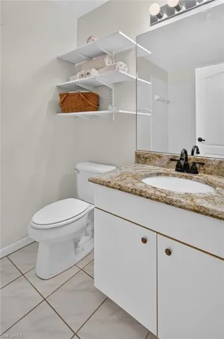 Bathroom featuring a white vanity with granite countertop, integrated sink, and dark-finish hardware