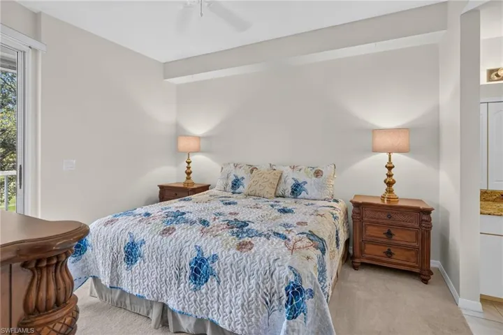 Carpeted bedroom featuring a ceiling fan, sliding glass door, and recessed shelving with a granite countertop