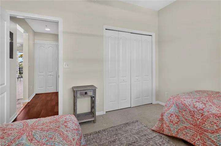 Neutral-toned room featuring a double bifold closet, light-colored carpet, and a hallway entrance with wood-finish flooring