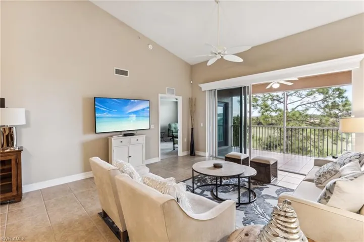 Living room featuring ceiling fan, light tile patterned flooring, and high vaulted ceiling