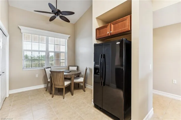 Kitchen featuring light tile patterned floors, ceiling fan, and black refrigerator with ice dispenser