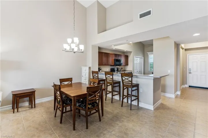 Dining area featuring a towering ceiling, a chandelier, and light tile patterned floors