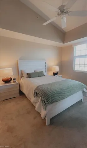 Bedroom featuring lofted ceiling, a ceiling fan, and light colored carpet