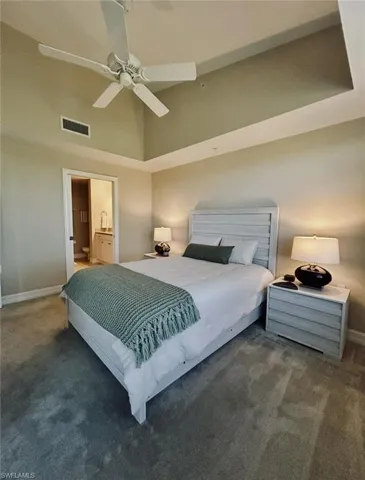 Bedroom with carpet floors, high vaulted ceiling, baseboards, and visible vents