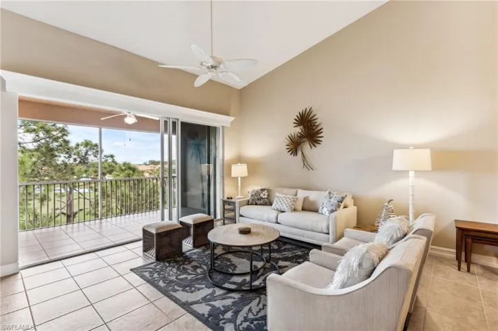 Living room featuring light tile patterned floors, vaulted ceiling, and ceiling fan