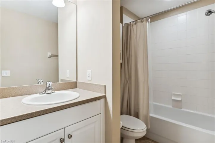 Full bathroom with vanity, shower / bath combo with shower curtain, and toilet