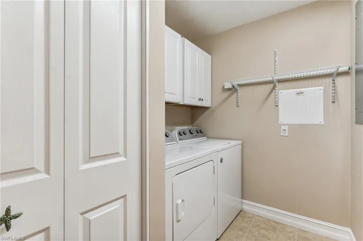 Laundry room featuring washer and clothes dryer, light tile patterned floors, and cabinets