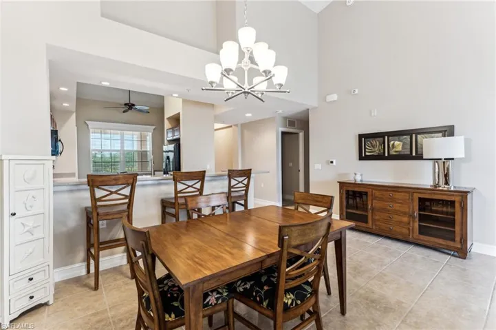 Dining space with ceiling fan with notable chandelier, a towering ceiling, and light tile patterned floors