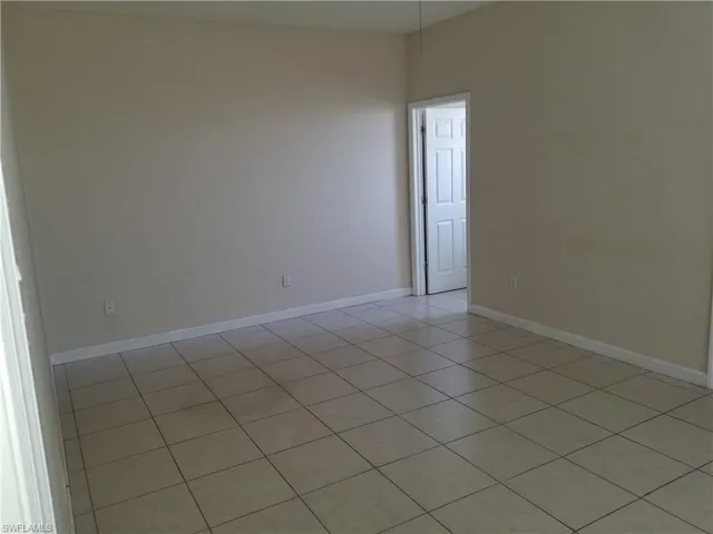 Empty room featuring baseboards and light tile patterned floors