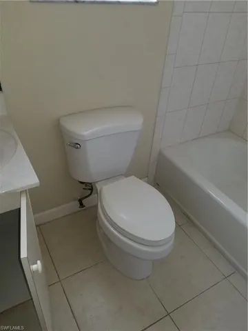 Full bathroom with vanity, light tile patterned flooring, and a tub to relax in
