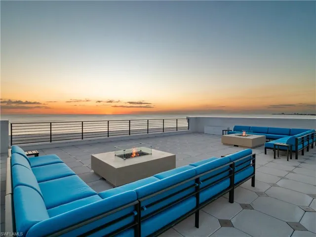 Patio terrace at dusk with an outdoor living space with a fire pit and a water view