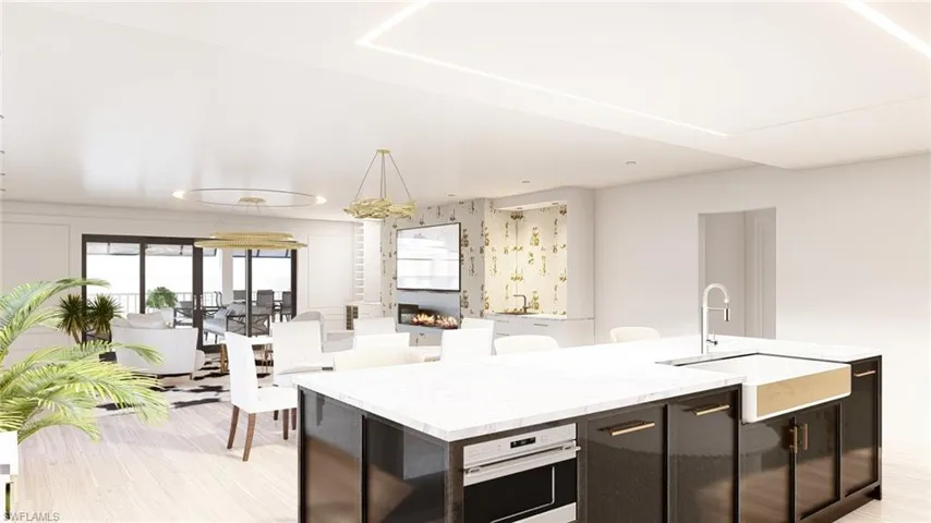 Kitchen with oven, sink, light wood-type flooring, an island with sink, and a large fireplace