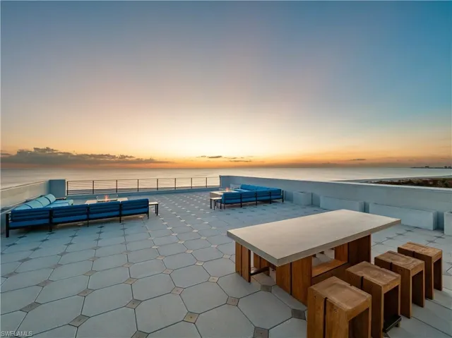 Patio terrace at dusk with outdoor lounge area and a water view