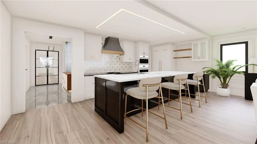 Kitchen with oven, white cabinetry, light hardwood / wood-style floors, decorative backsplash, and a kitchen island with sink