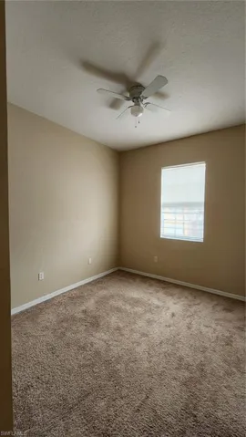 Carpeted spare room with a textured ceiling and ceiling fan