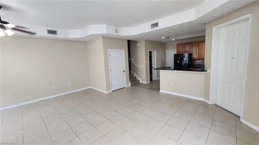 Kitchen featuring light tile patterned floors, black refrigerator, and ceiling fan