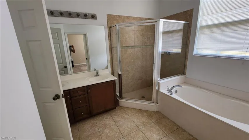 Bathroom featuring vanity, tile patterned floors, and shower with separate bathtub