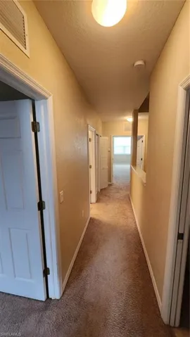 Hall featuring carpet and a textured ceiling