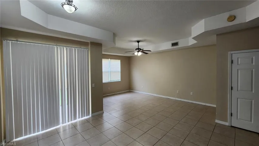 Empty room featuring a textured ceiling, light tile patterned floors, and ceiling fan