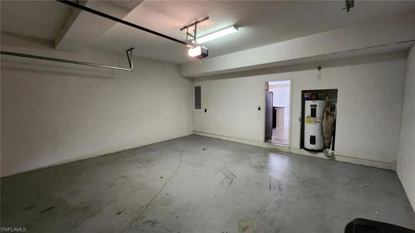 Garage featuring electric water heater, a garage door opener, and electric panel