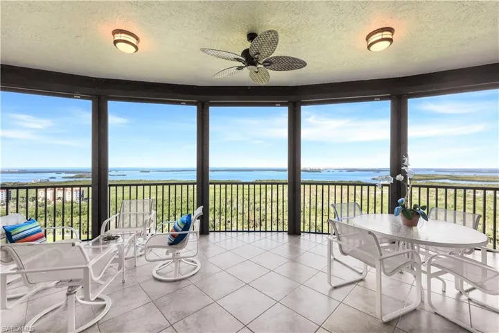 Unfurnished sunroom featuring a water view, ceiling fan, and a wealth of natural light