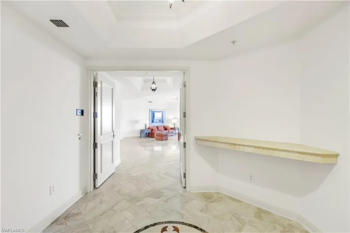 Corridor with crown molding and a tray ceiling
